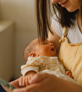 A mother gently cradling her newborn baby in her arms, sharing a tender moment filled with warmth and love in a softly lit setting.