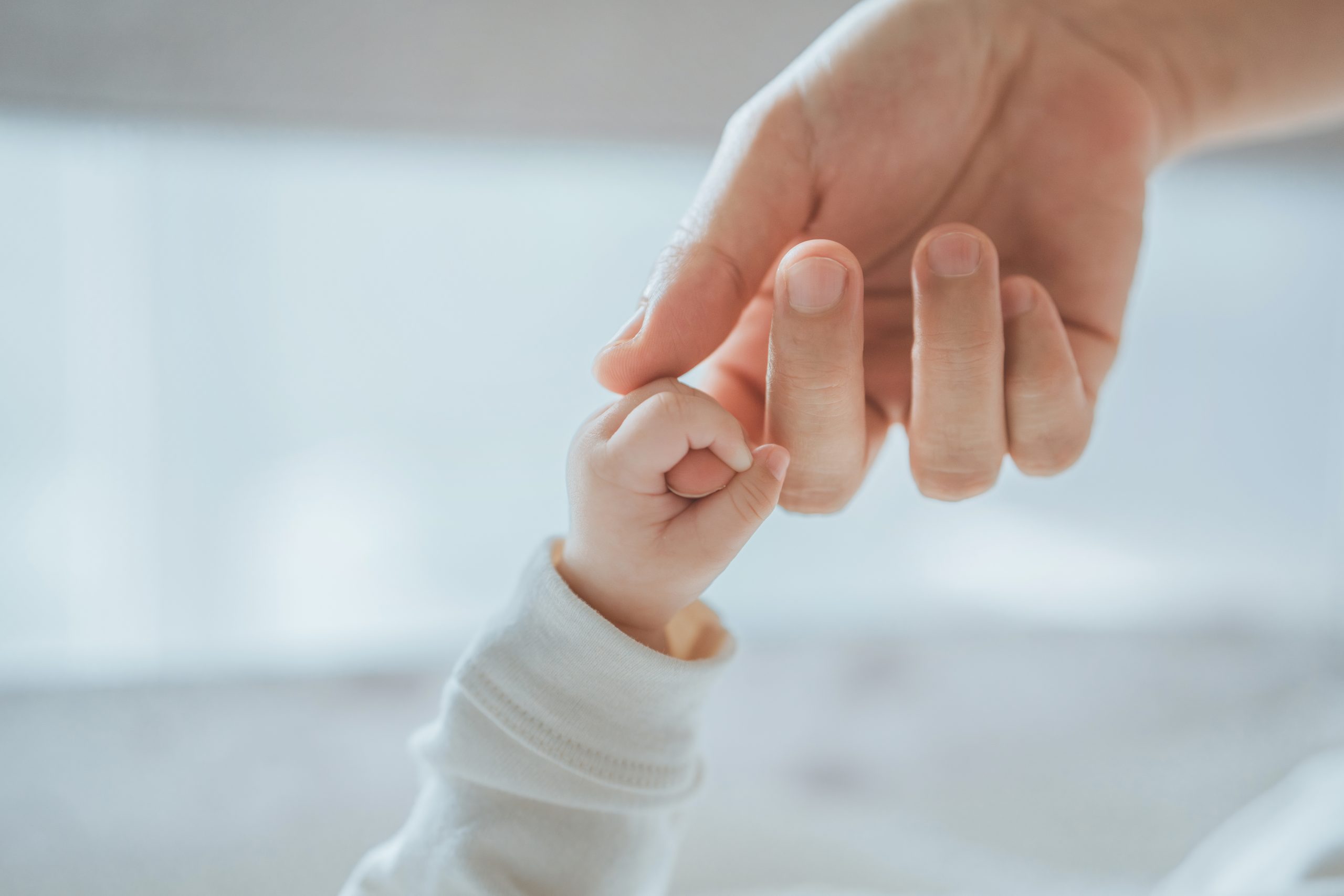 Close-up little hand of child baby holding hand of mother, A newborn holds on to mom&rsquo;s, dad&rsquo;s finger, Love and relationship with infant, Care and support, Dreaming and protection